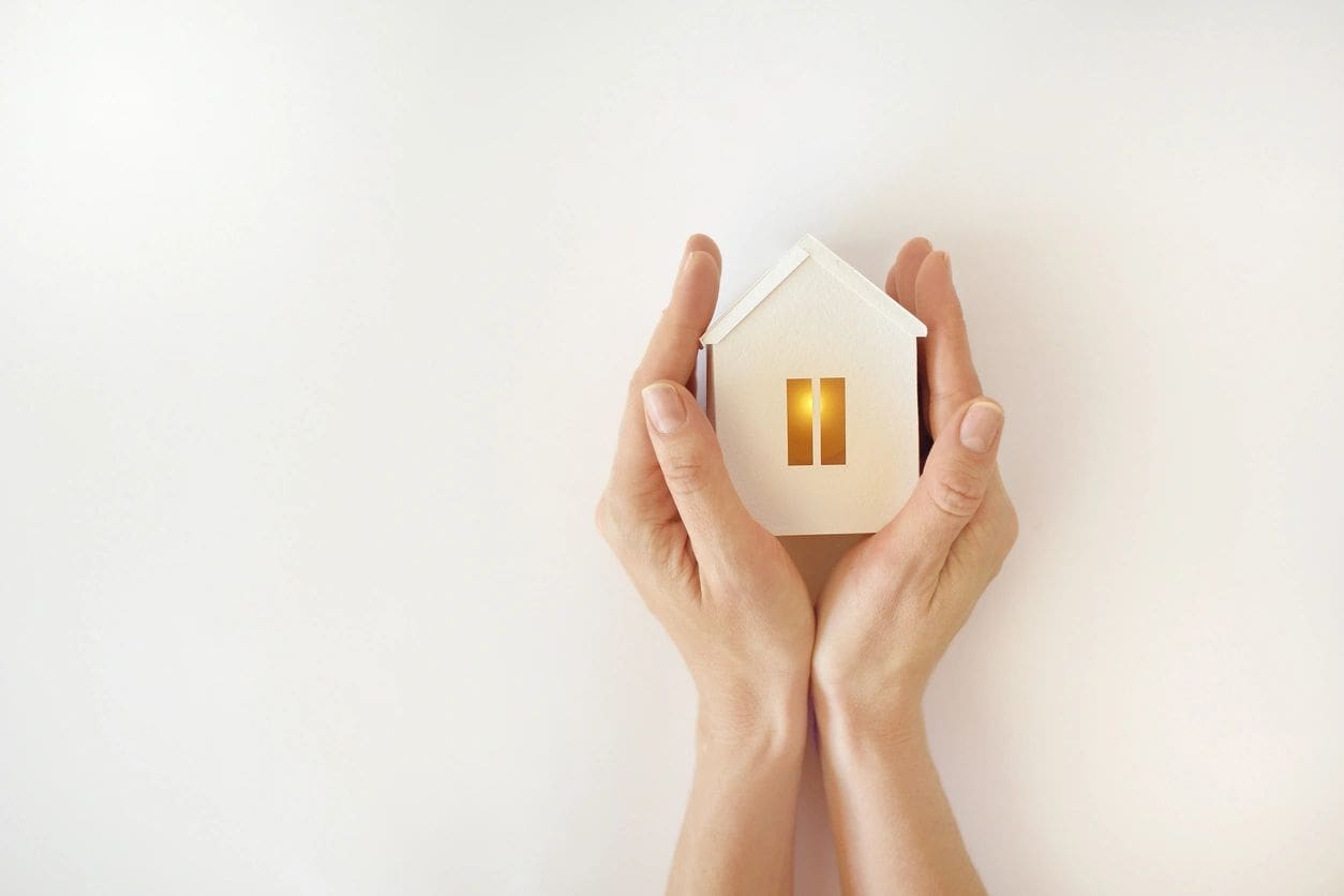 A person holding a small house in their hands.