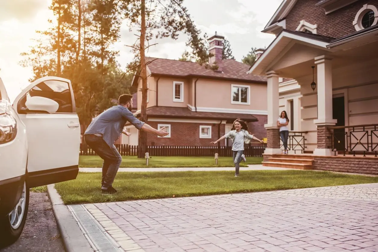 A man and boy playing frisbee in front of their home.