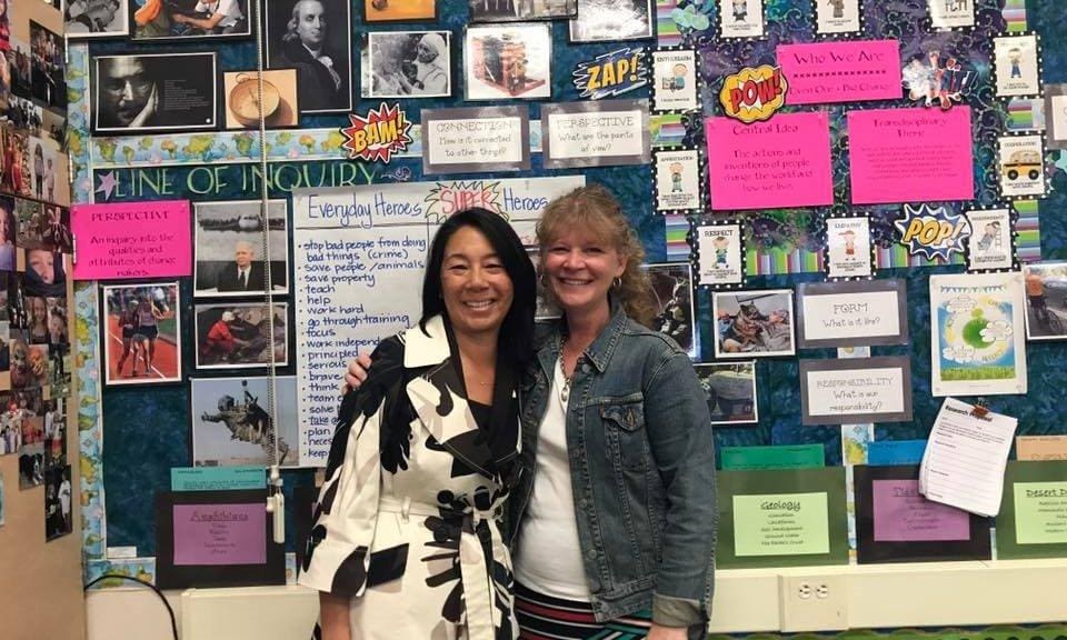 Two women standing in front of a wall covered with pictures.